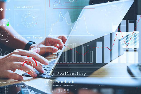 Hands typing on a laptop keyboard with blue transparent digital overlays displaying business charts and data.
