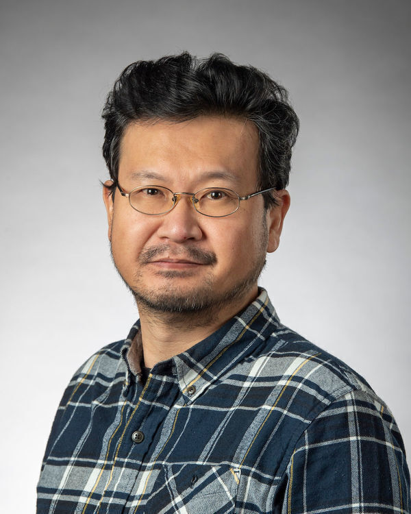 Headhsot of Dae Kun Kwon, a man with glasses, short dark hair, and light stubble wears a blue, white, and yellow plaid shirt.